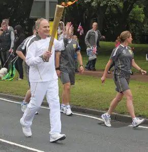 Founder Derek Wilcox carries the Olympic Torch for services to coaching young athletes in the region.